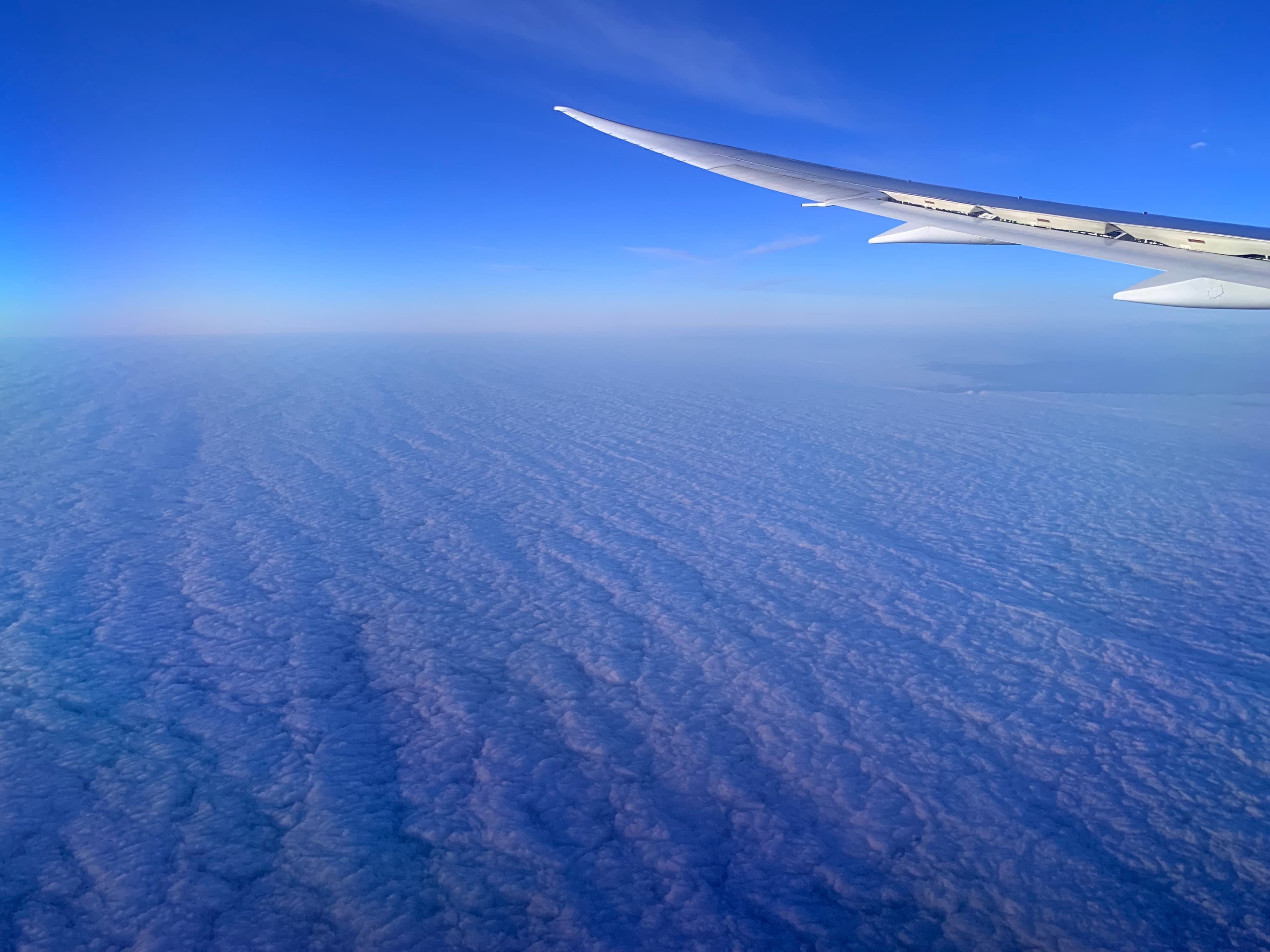 view from airplane flying over the ocean with clouds